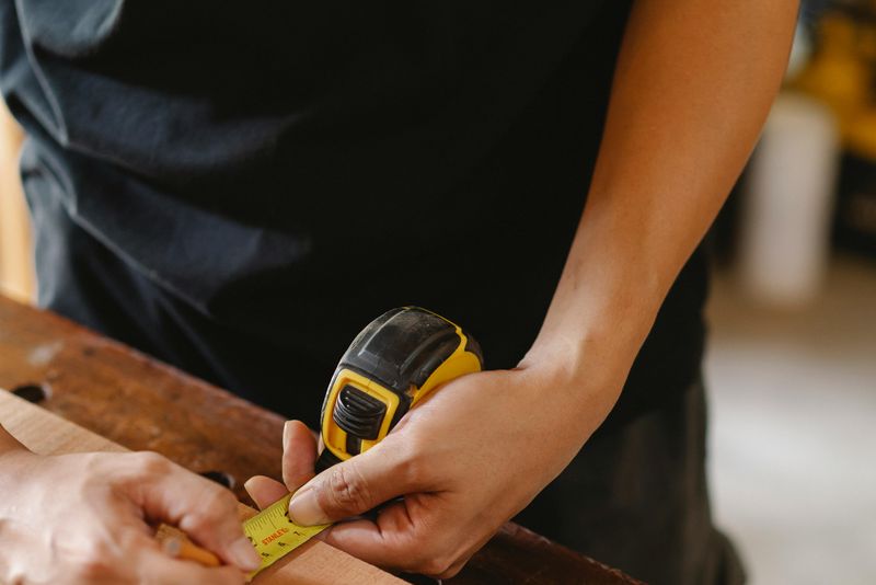 Vakman meet houten plank op — opmeting voor deurbestelling
